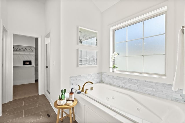 full bath with a walk in closet and a whirlpool tub