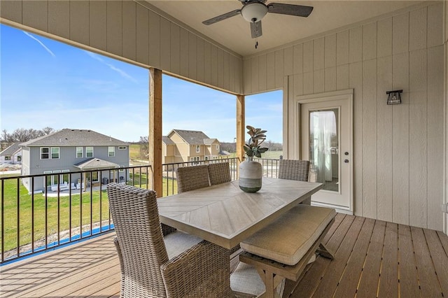 sunroom featuring a ceiling fan and a residential view