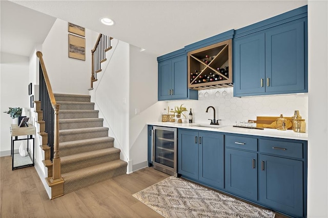 bar with a sink, backsplash, wine cooler, light wood-style floors, and indoor wet bar