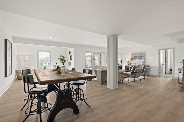 dining area with recessed lighting, decorative columns, baseboards, and light wood finished floors