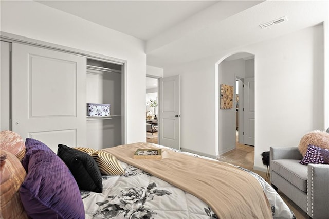 bedroom featuring arched walkways, visible vents, baseboards, and a closet