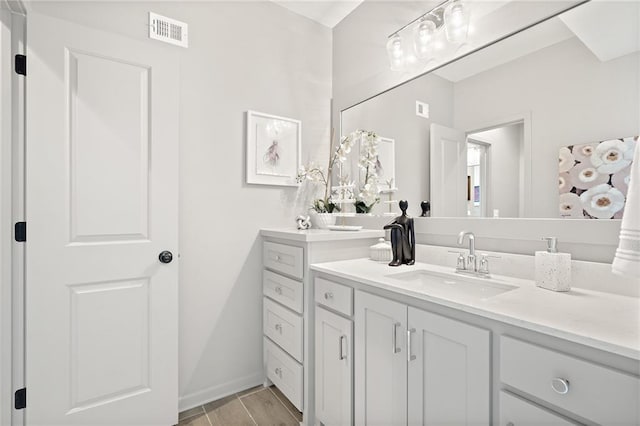 bathroom featuring vanity, wood finished floors, visible vents, and baseboards