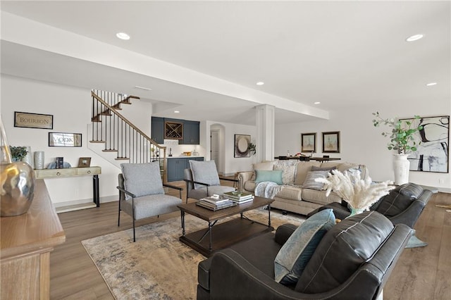 living room with stairway, wood finished floors, baseboards, decorative columns, and recessed lighting