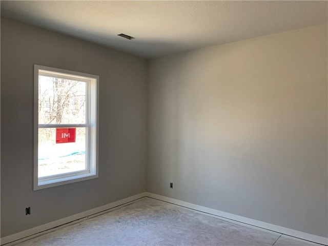 spare room featuring visible vents, baseboards, and concrete flooring