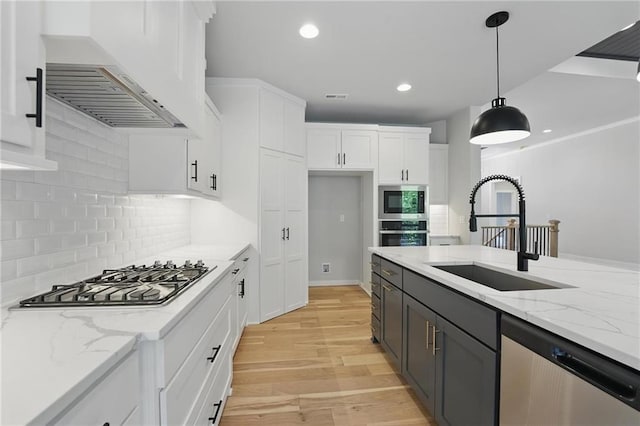 1406 NW 106th Ter, Kansas City, MO 64155 - kitchen with stainless steel appliances, premium range hood, white cabinetry, light wood-style flooring, and hanging light fixtures