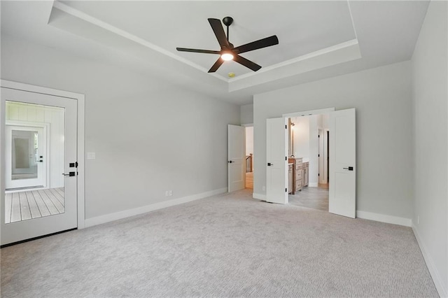 1406 NW 106th Ter, Kansas City, MO 64155 - unfurnished bedroom featuring a tray ceiling, light colored carpet, connected bathroom, and ceiling fan