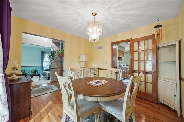 dining space featuring a notable chandelier, wood finished floors, and visible vents