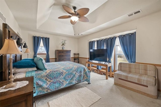 bedroom with visible vents, a ceiling fan, a tray ceiling, and carpet floors