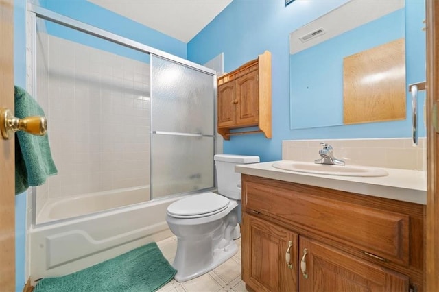 bathroom featuring tile patterned flooring, visible vents, toilet, combined bath / shower with glass door, and vanity