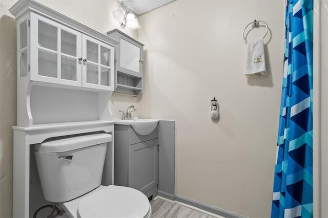 bathroom featuring curtained shower, baseboards, toilet, wood finished floors, and vanity