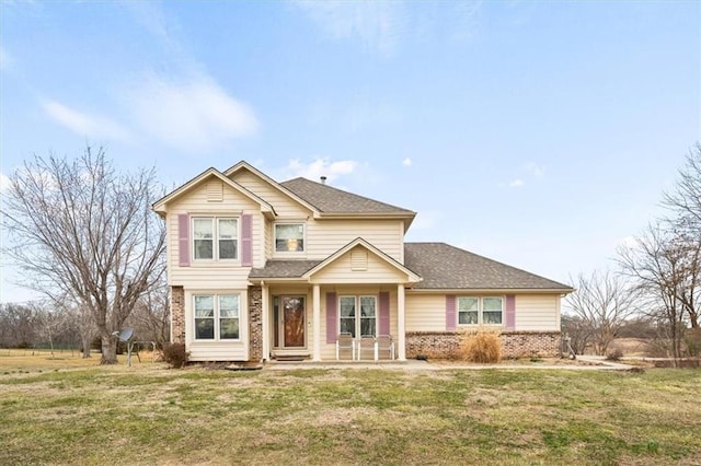 view of front of home with a front yard, brick siding, and roof with shingles