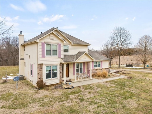 view of front of home featuring a front lawn, a shingled roof, brick siding, central AC unit, and a chimney