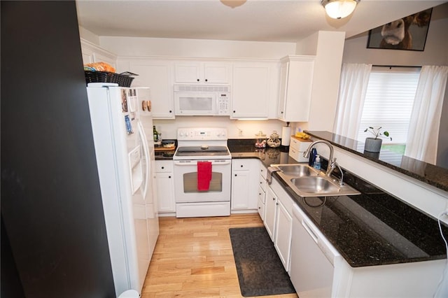 kitchen with sink, white appliances, dark stone counters, light hardwood / wood-style floors, and white cabinets