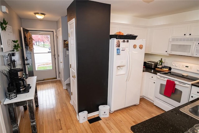 kitchen with white cabinetry, white appliances, light hardwood / wood-style flooring, and dark stone counters