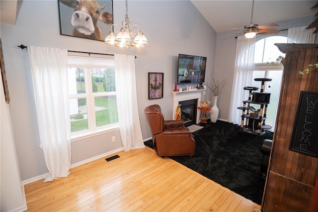 living room with lofted ceiling, hardwood / wood-style flooring, plenty of natural light, and ceiling fan with notable chandelier