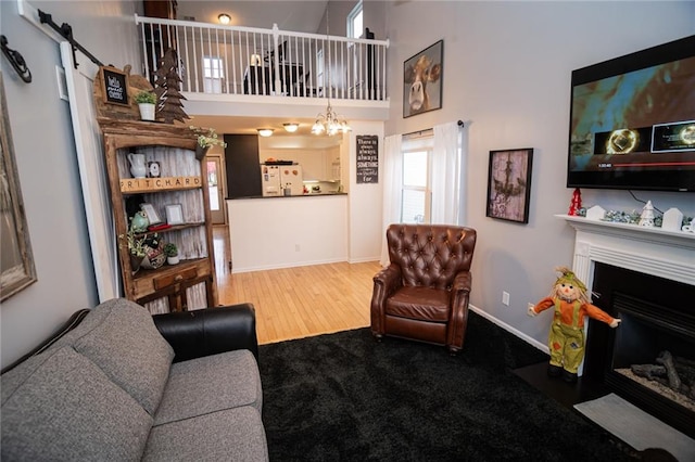 living room with wood-type flooring, a barn door, and a towering ceiling