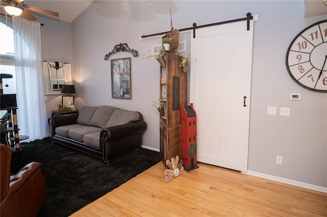 living room with ceiling fan, wood-type flooring, and a barn door