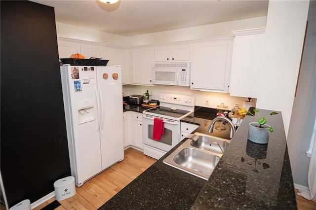 kitchen with light wood finished floors, white appliances, a sink, and white cabinetry