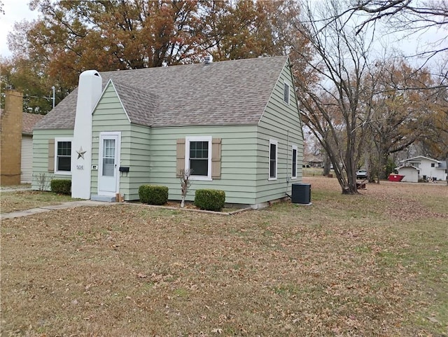 cape cod home with cooling unit and a front yard