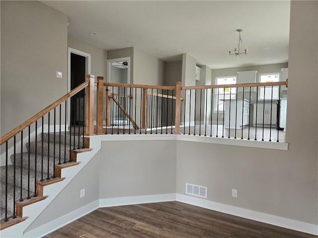 stairs featuring ceiling fan with notable chandelier and wood-type flooring