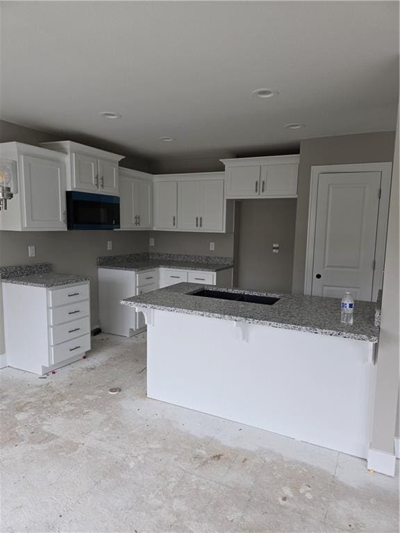 kitchen with stone counters, white cabinetry, and a breakfast bar