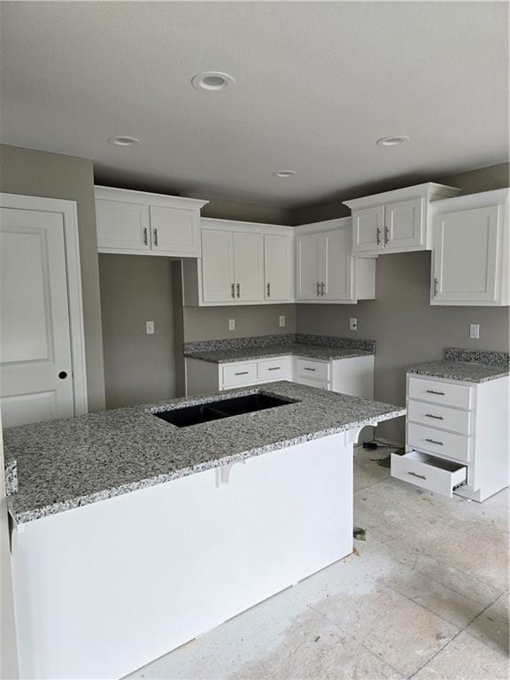 kitchen featuring stone counters, a center island, and white cabinetry