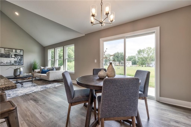 dining space featuring wood-type flooring, lofted ceiling, and a chandelier