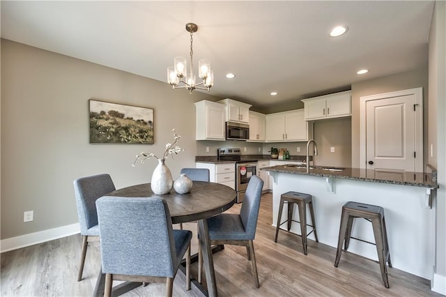 dining room featuring light wood-type flooring, a notable chandelier, and sink