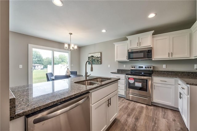 kitchen featuring white cabinetry, sink, stainless steel appliances, decorative light fixtures, and light wood-type flooring