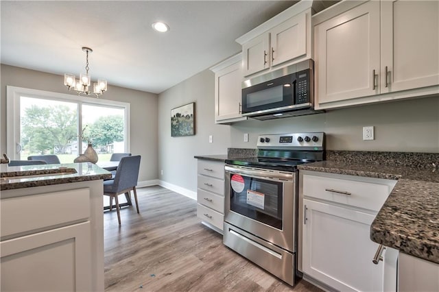 kitchen with white cabinetry, a notable chandelier, decorative light fixtures, appliances with stainless steel finishes, and light wood-type flooring