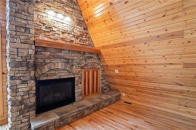 room details with a stone fireplace, wooden walls, and hardwood / wood-style floors