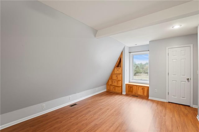 additional living space with vaulted ceiling with beams and light hardwood / wood-style flooring