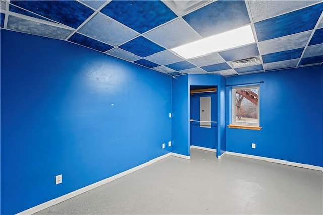 spare room featuring a drop ceiling and concrete flooring