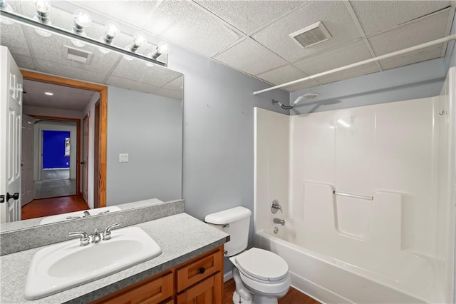 full bathroom with a drop ceiling, bathing tub / shower combination, toilet, vanity, and hardwood / wood-style flooring