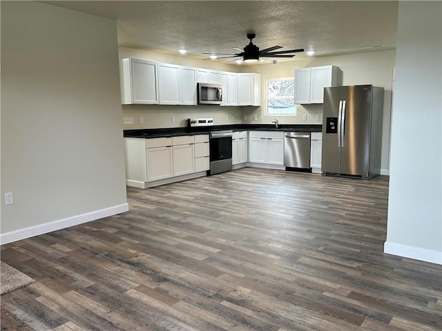 kitchen featuring white cabinets, a textured ceiling, dark hardwood / wood-style flooring, and stainless steel appliances