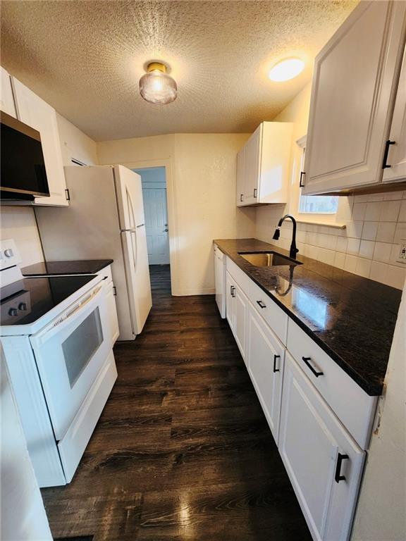 kitchen featuring dark hardwood / wood-style floors, sink, white cabinets, white appliances, and a textured ceiling