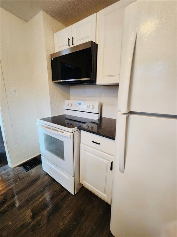 kitchen with dark hardwood / wood-style floors, tasteful backsplash, white cabinets, white appliances, and a textured ceiling