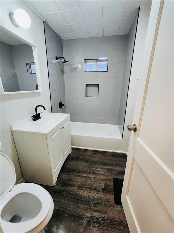 bathroom with wood-type flooring, a tile shower, and vanity