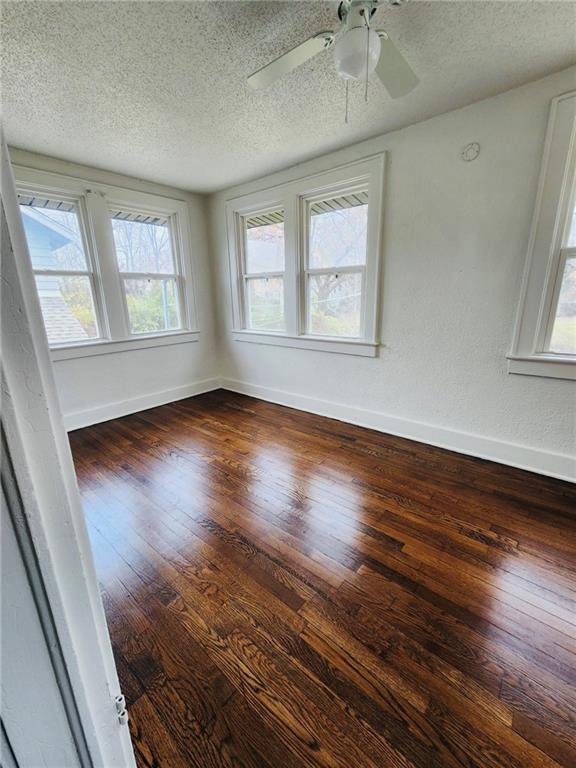 unfurnished room featuring ceiling fan, a textured ceiling, and dark hardwood / wood-style flooring