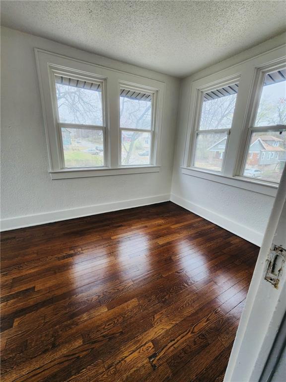 spare room featuring dark wood-type flooring, plenty of natural light, and a textured ceiling