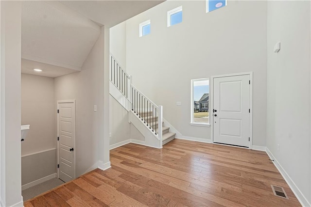 foyer entrance with a wealth of natural light, light hardwood / wood-style flooring, and high vaulted ceiling