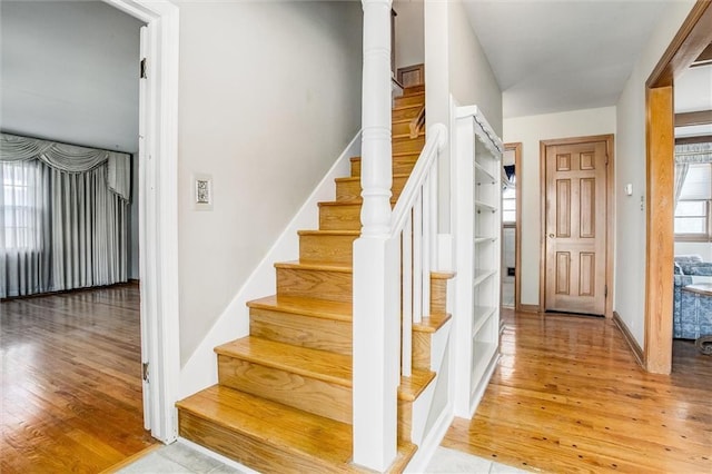 stairs with ornate columns and wood-type flooring