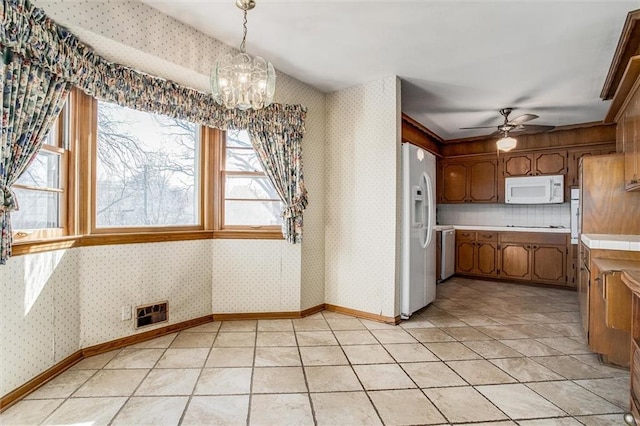 kitchen featuring backsplash, ceiling fan with notable chandelier, white appliances, light tile patterned floors, and decorative light fixtures