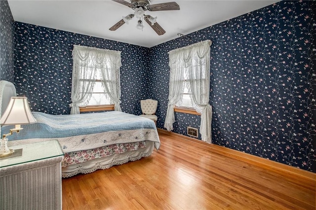 bedroom with hardwood / wood-style flooring, ceiling fan, and multiple windows