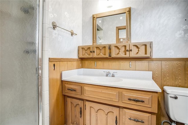 bathroom featuring vanity, toilet, a shower with shower door, and wood walls