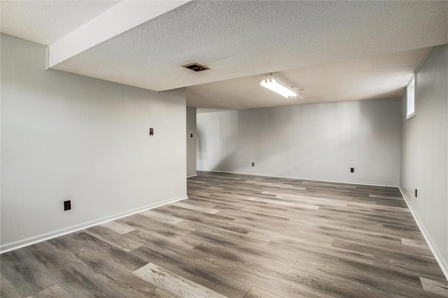 basement with hardwood / wood-style floors and a textured ceiling