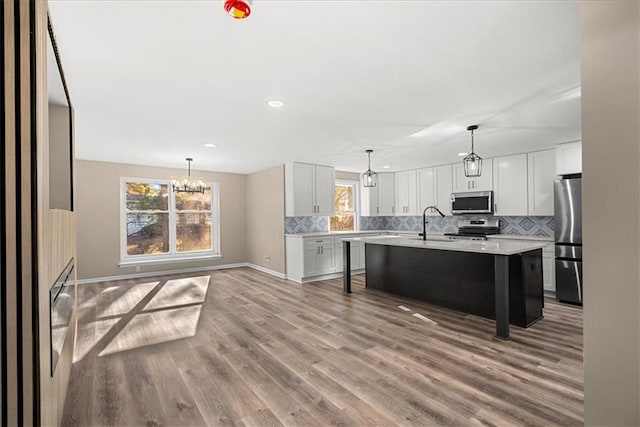 kitchen with hardwood / wood-style floors, white cabinetry, stainless steel appliances, and a kitchen island with sink