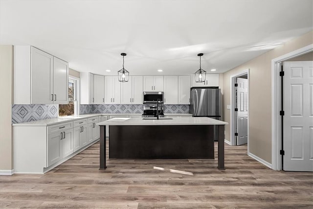 kitchen with light hardwood / wood-style floors, a center island, pendant lighting, and appliances with stainless steel finishes