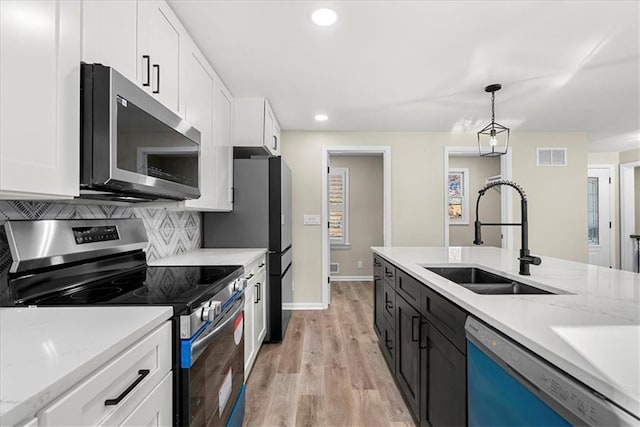 kitchen featuring pendant lighting, white cabinetry, sink, and stainless steel appliances