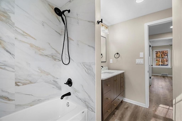 bathroom featuring wood-type flooring, vanity, and tiled shower / bath